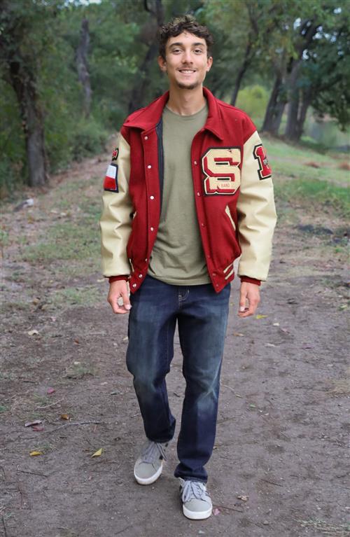 A boy in his late teens walks in the woods